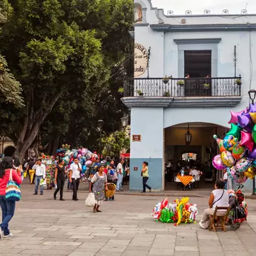 Oaxaca, Mexico - May 7, 2014: Some locals in the Zocalo (Town Square). A street vendor selling colorful balloons.
