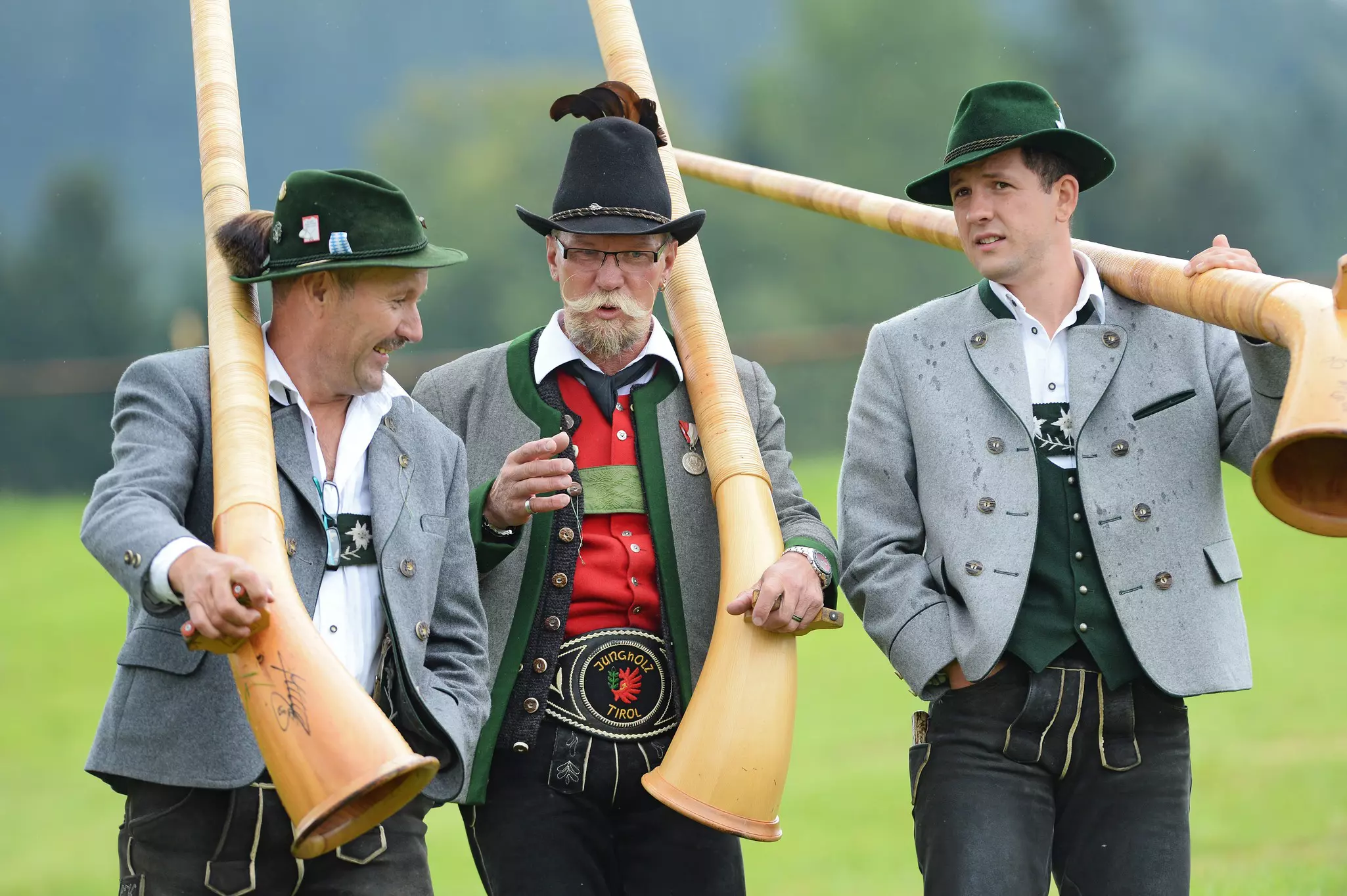 Three Alpenhorn blowers carrying their instruments © Felix Kästle / picture alliance / Getty Images