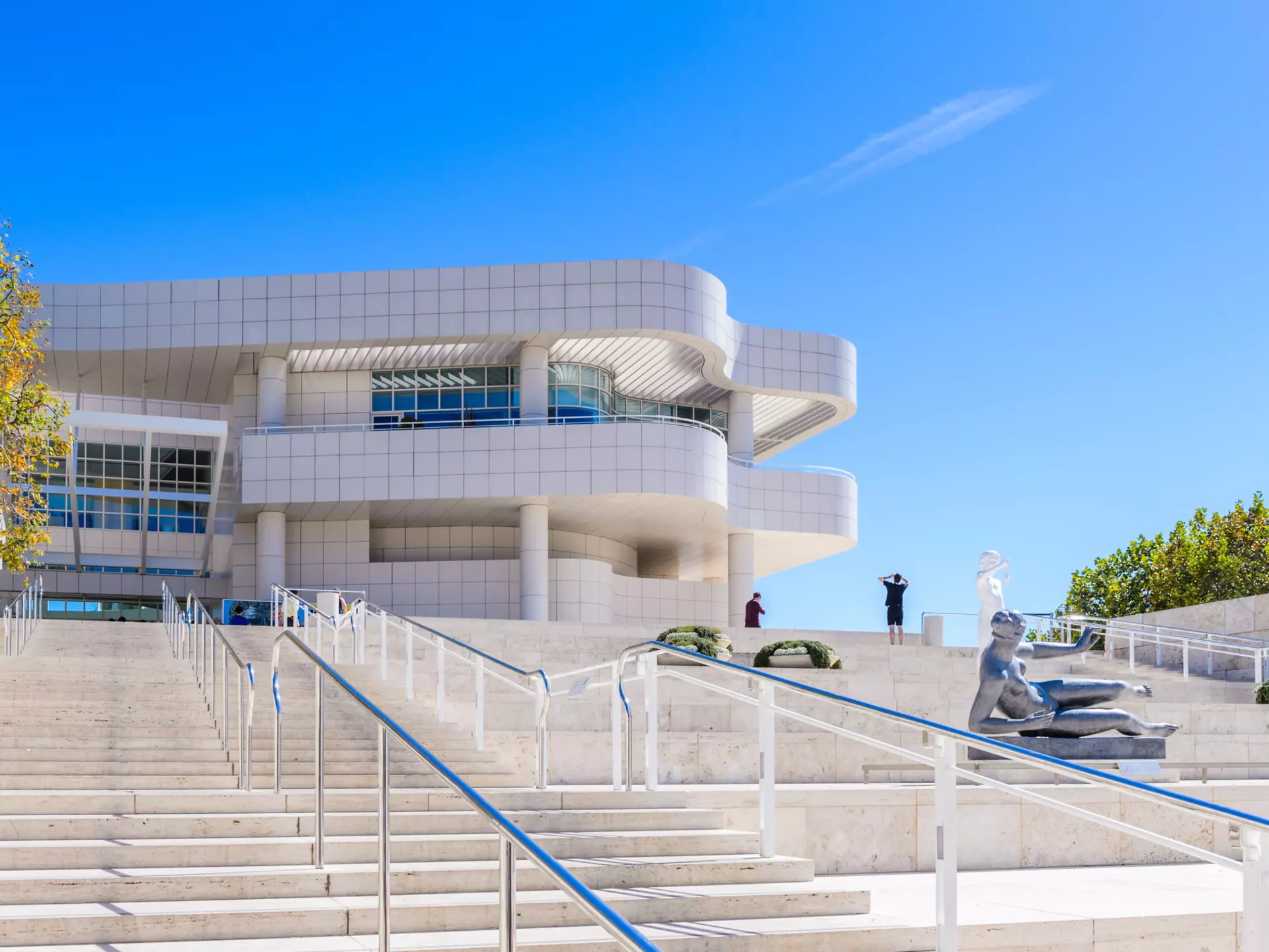 Sculptures are seen on a huge set of steps leading to an ultra-modern building. 