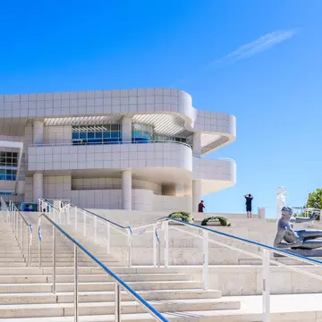 Sculptures are seen on a huge set of steps leading to an ultra-modern building. 