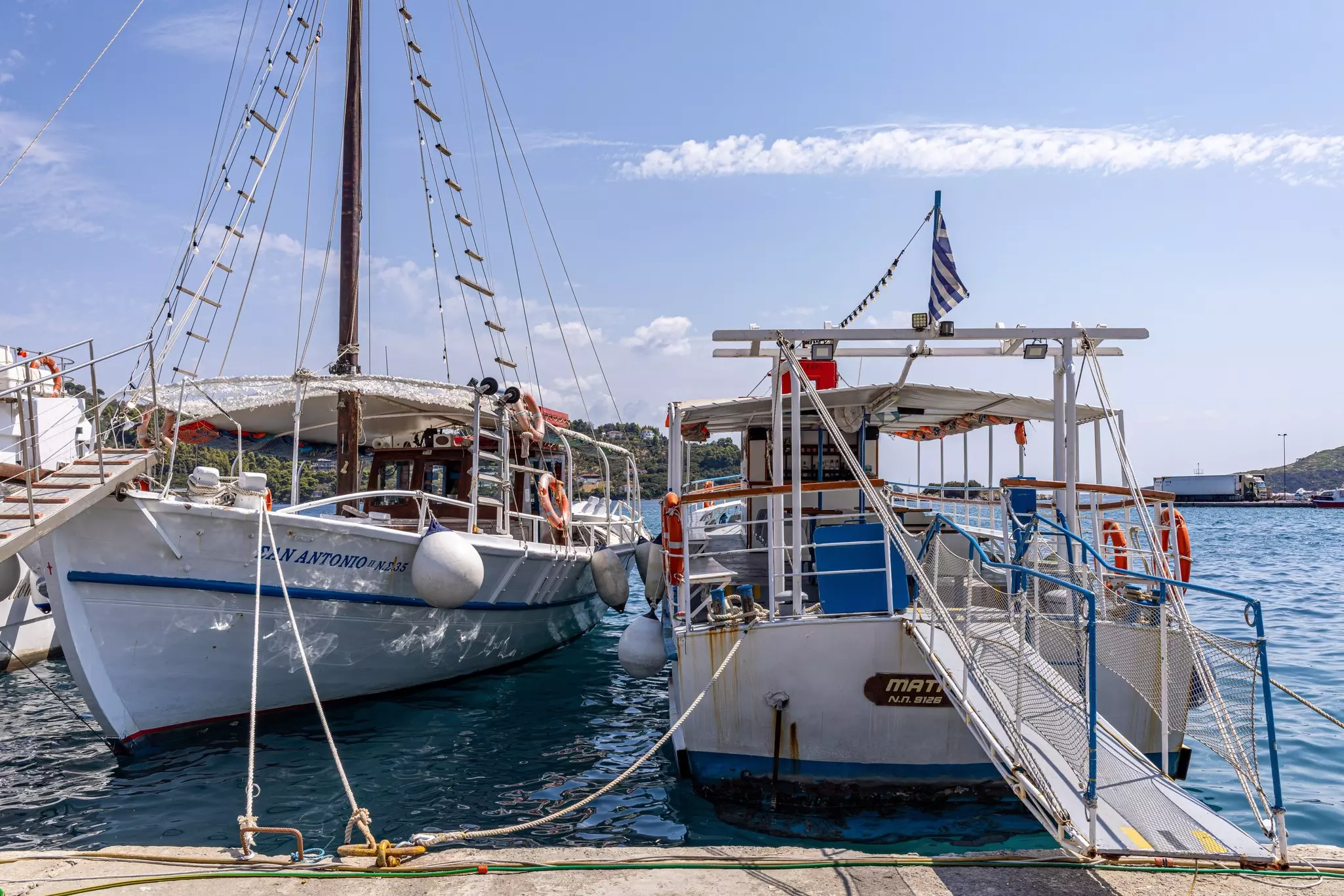 Two large boats are moored at a marina in a town.