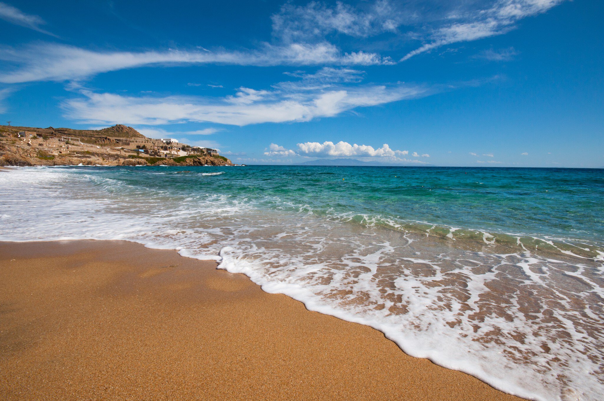 View of waves washing onto Paradise Beach on the island of Mykonos in Greece.