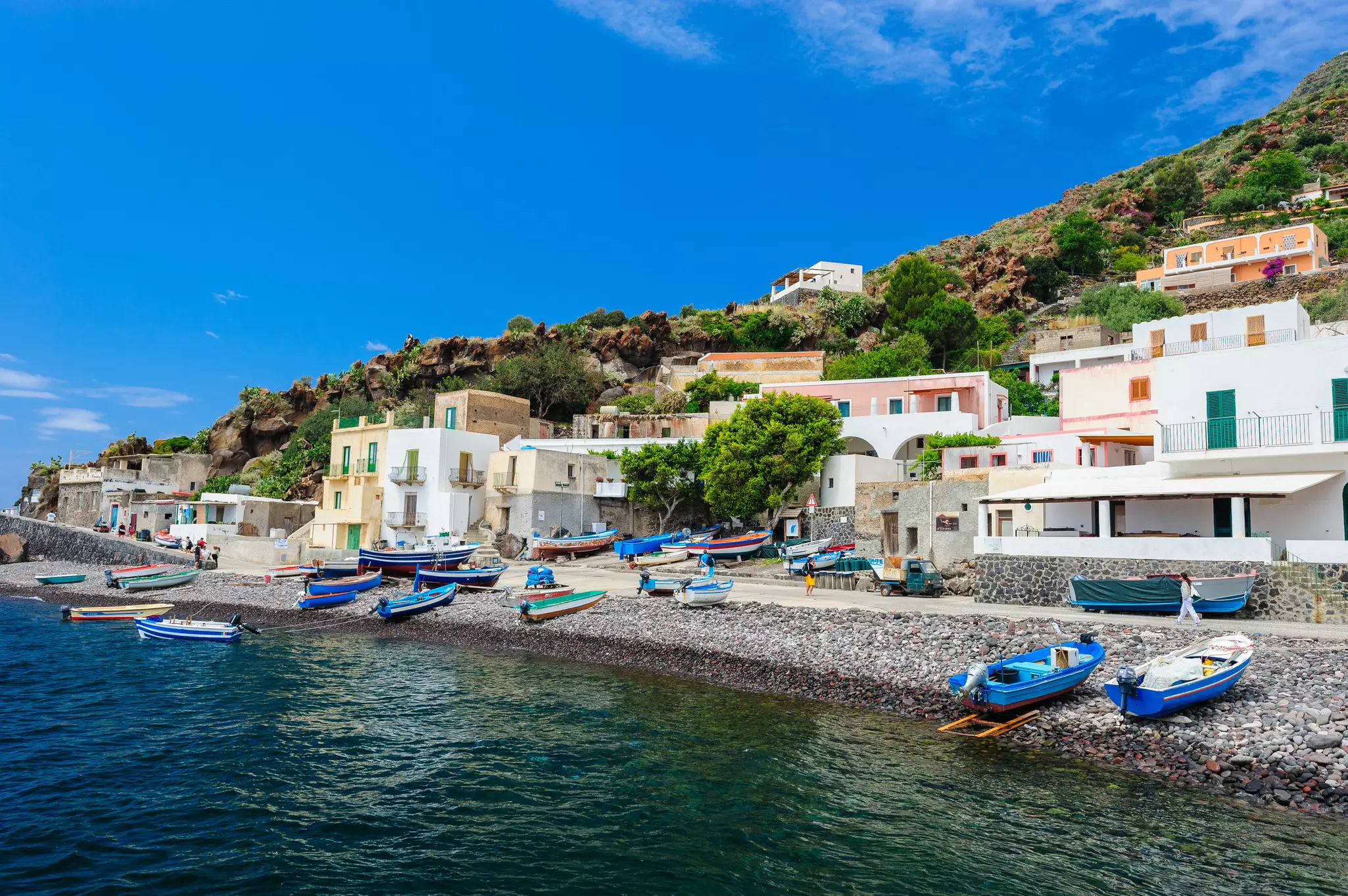 Colorful wooden fishing boats moored on a pebbly coastline.