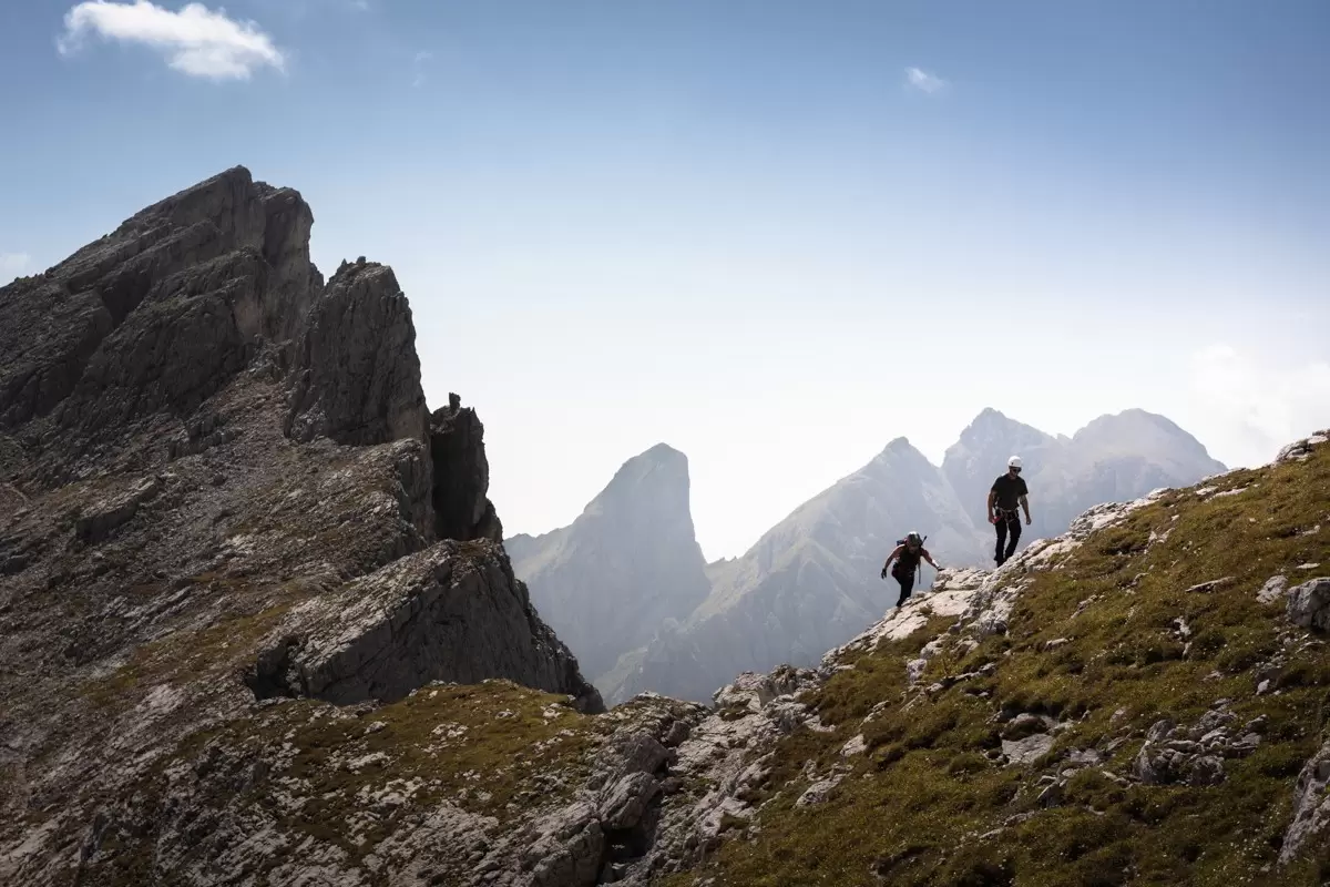 Two hikers looking out over the rocky peaks in the Dolomites in Veneto, Italy.