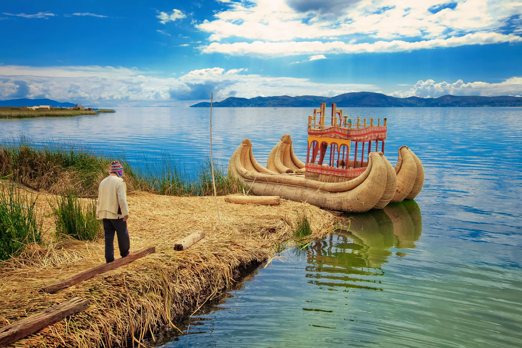 A man walks towards the reed boats on the island of Uros, Puno, Peru