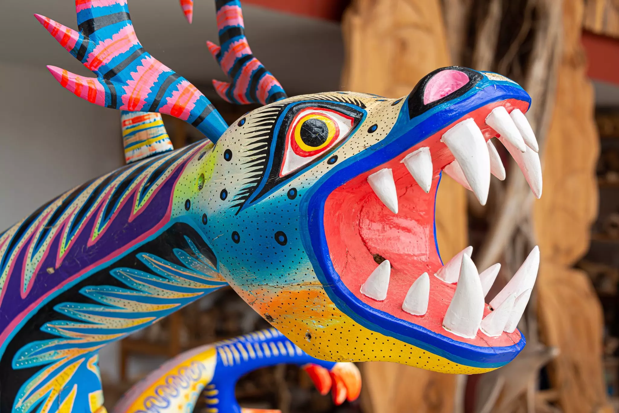 Close-up of fantastically colorful painted wood dragon with an open mouth and big white teeth.
