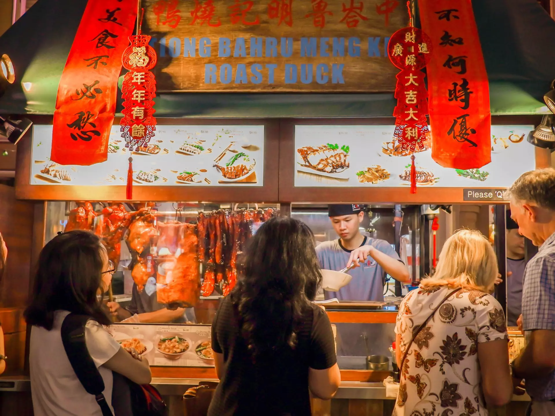 A crowd of people in front of a traditional noodle shop in Chinatown, Singapore. 