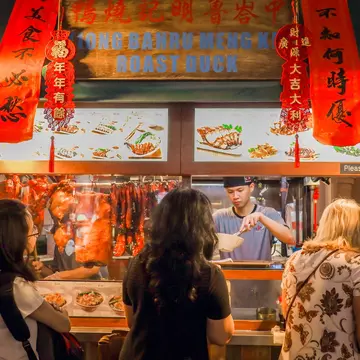 A crowd of people in front of a traditional noodle shop in Chinatown, Singapore. 