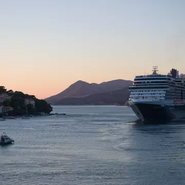 A cruise ship sails from a port at dusk