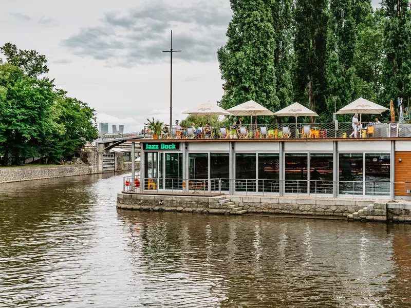 Prague, Czech Republic-August 4,2021.Jazz Dock music club on Vltava river.Concerts,performances,live music,relaxed summer atmosphere.People drinking,talking,having fun on terrace of the club  License Type: media  Download Time: 2023-08-06T11:35:34.000Z  User: hannahblackie10  Is Editorial: Yes  purchase_order:   