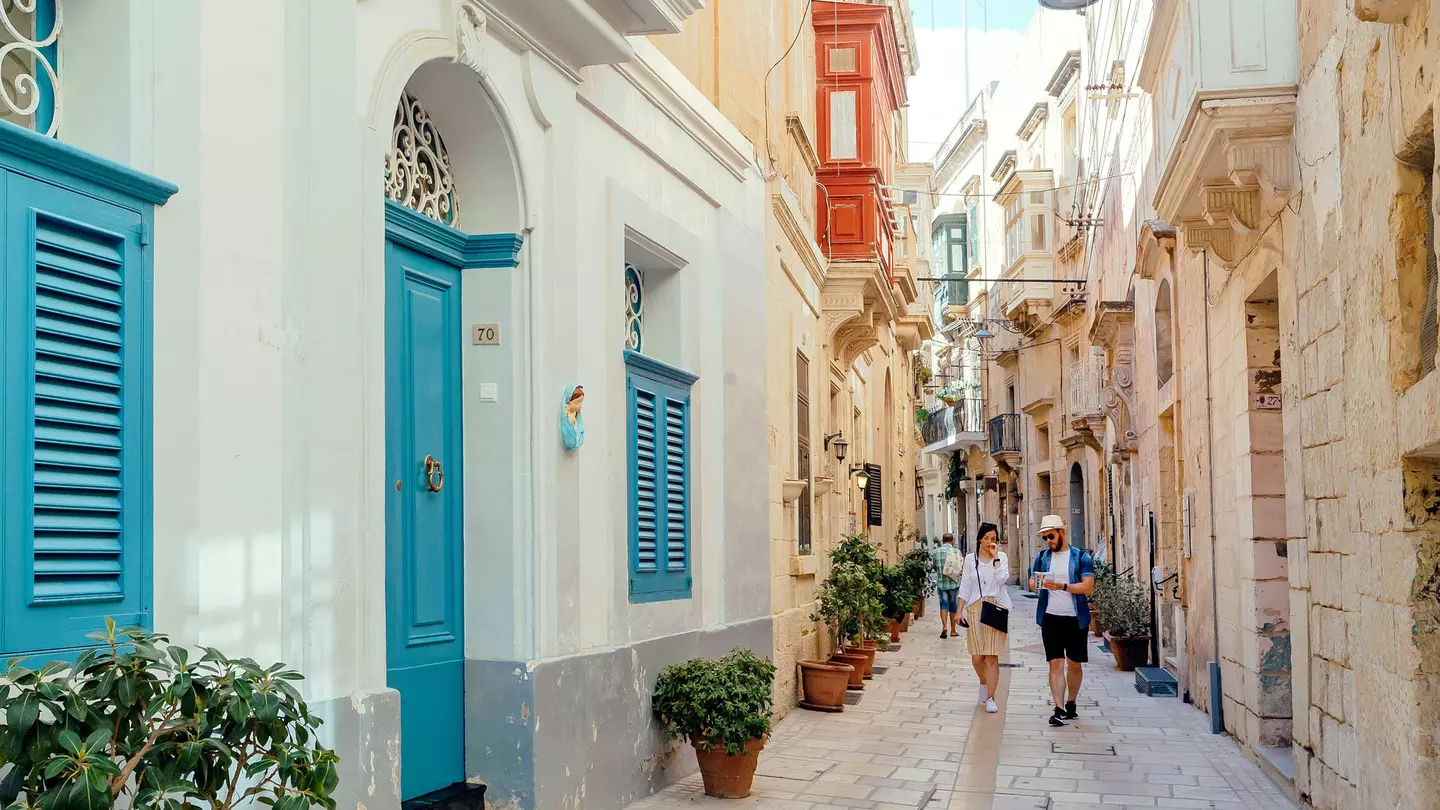 Tourists walking down narrow streets with wooden doors and historical houses