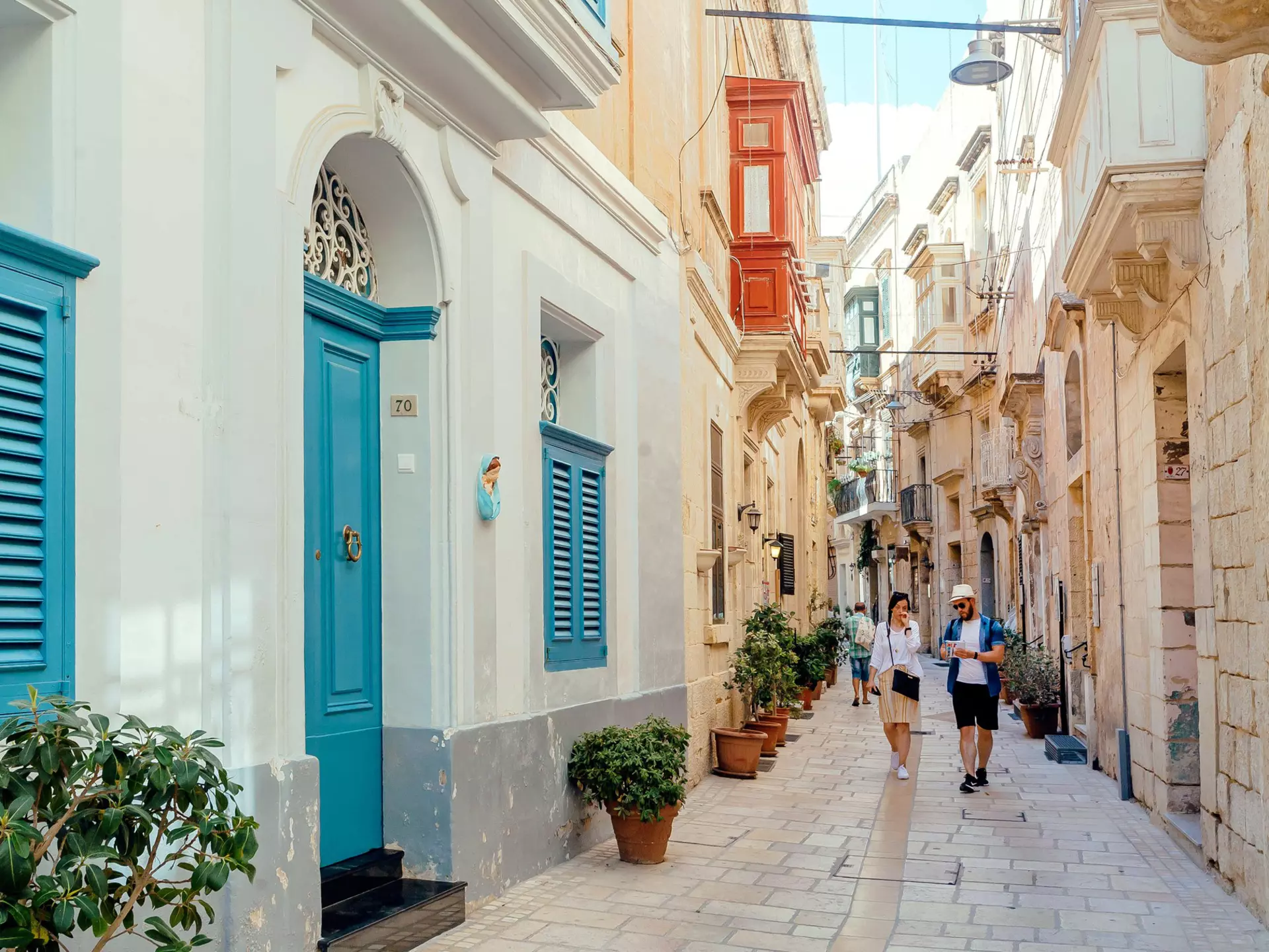 Tourists walking down narrow streets with wooden doors and historical houses