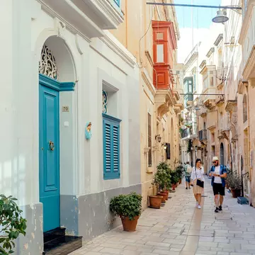 Tourists walking down narrow streets with wooden doors and historical houses