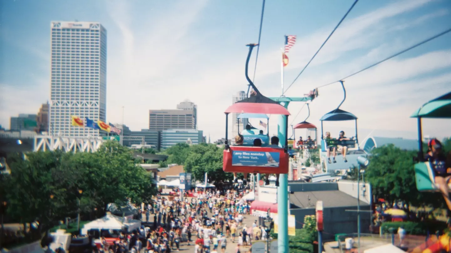 A gondola at Henry Maier Festival Park soars above crowds below and the skyline in the distance at Summerfest, Milwaukee, Wisconsin, USA