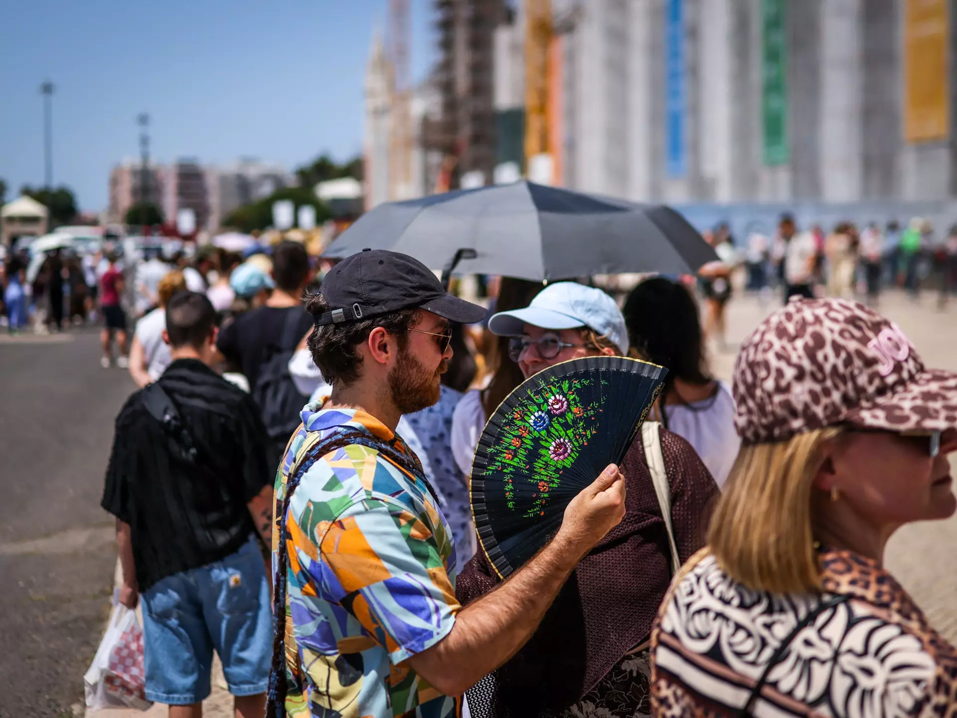 Tourists try to beat the heat with hand fans as they queue in Belém, Lisbon. 