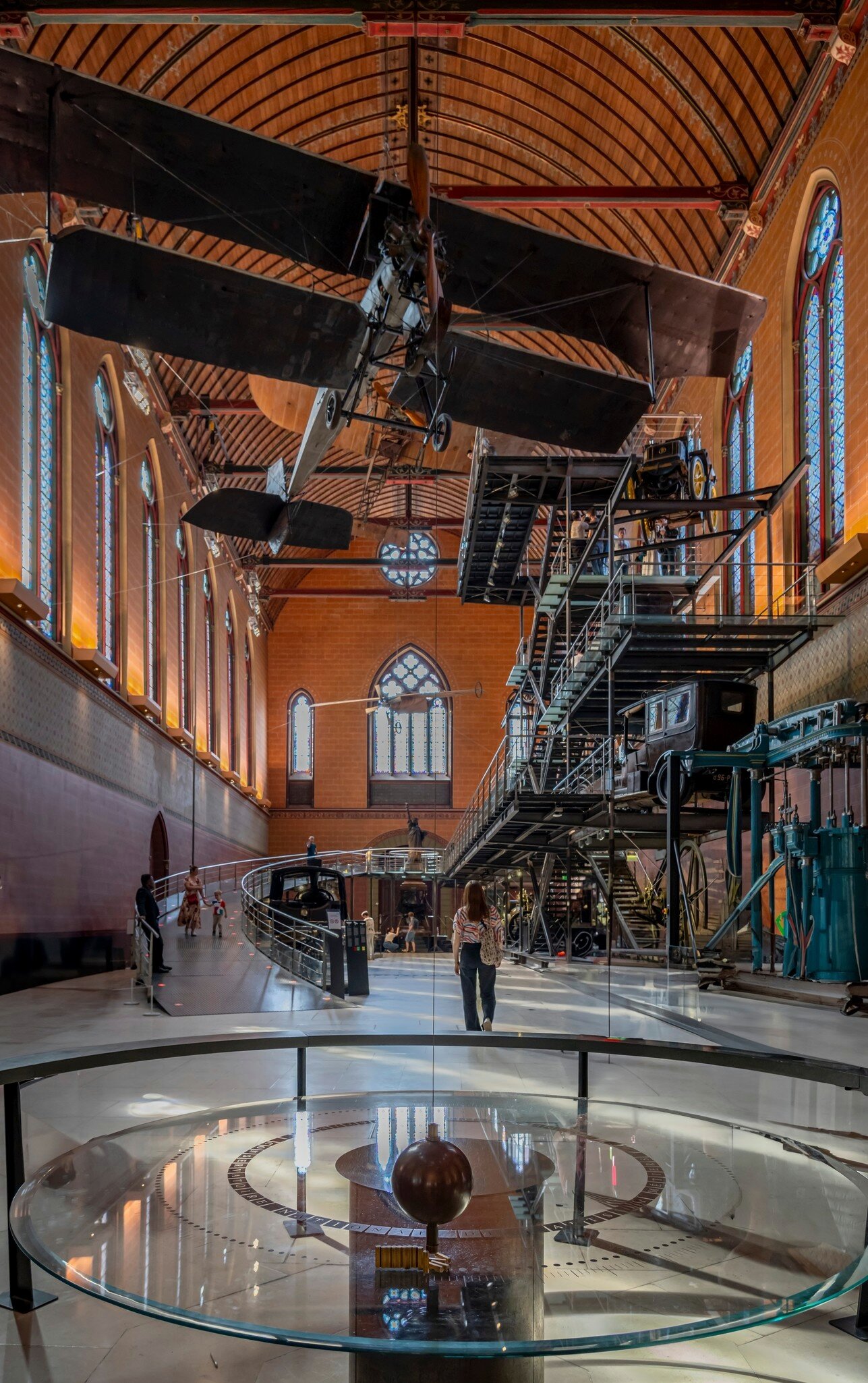 A woman walking through the Museum of Arts and Crafts with the Foucault pendulum from the church of Saint-Martin-Des-Champs in the foreground.