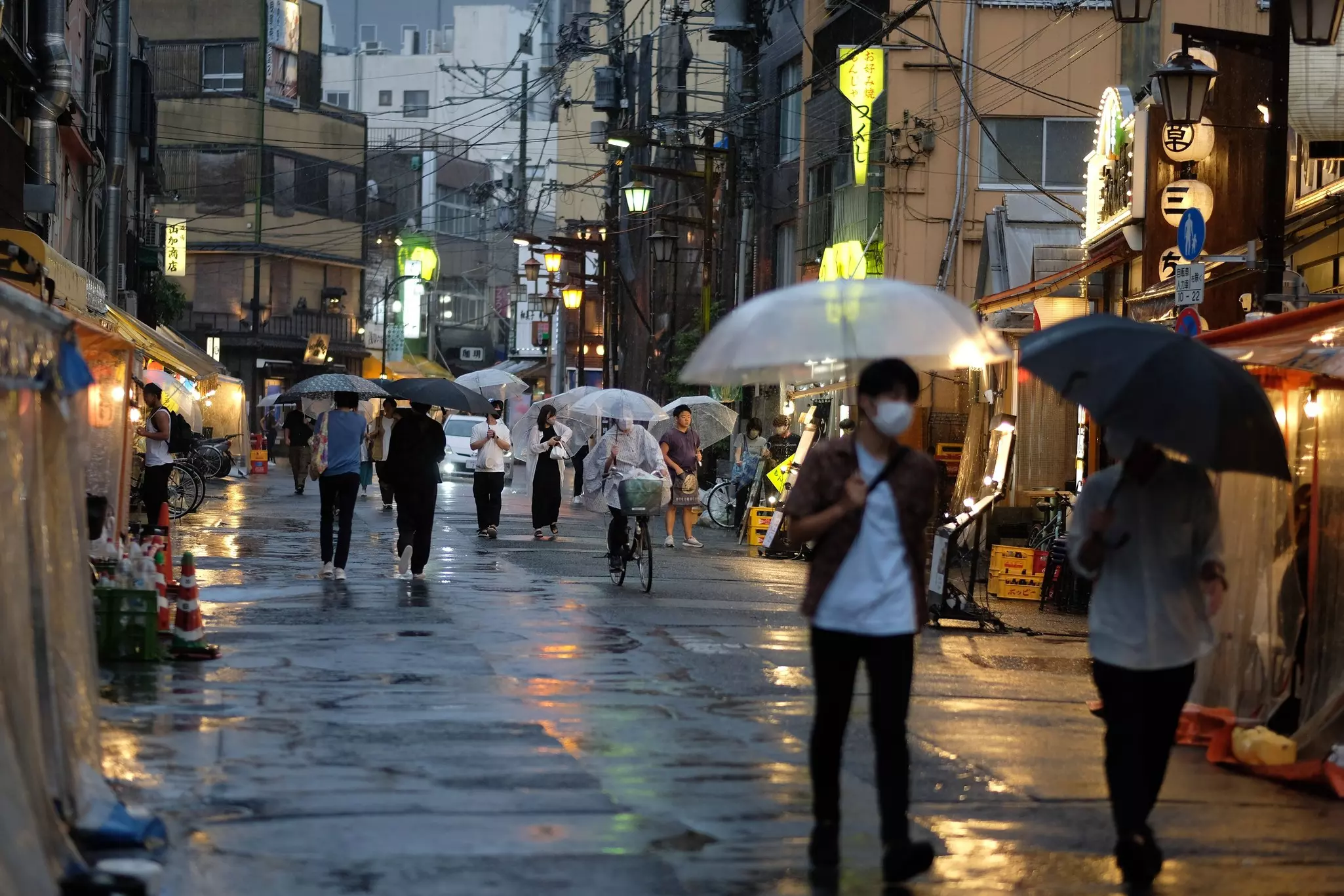 People with umbrellas walking in the rain at dusk in Asakusa, Tokyo, Japan.