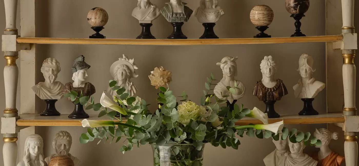 shelves of busts with a bouquet of flowers on a table in front