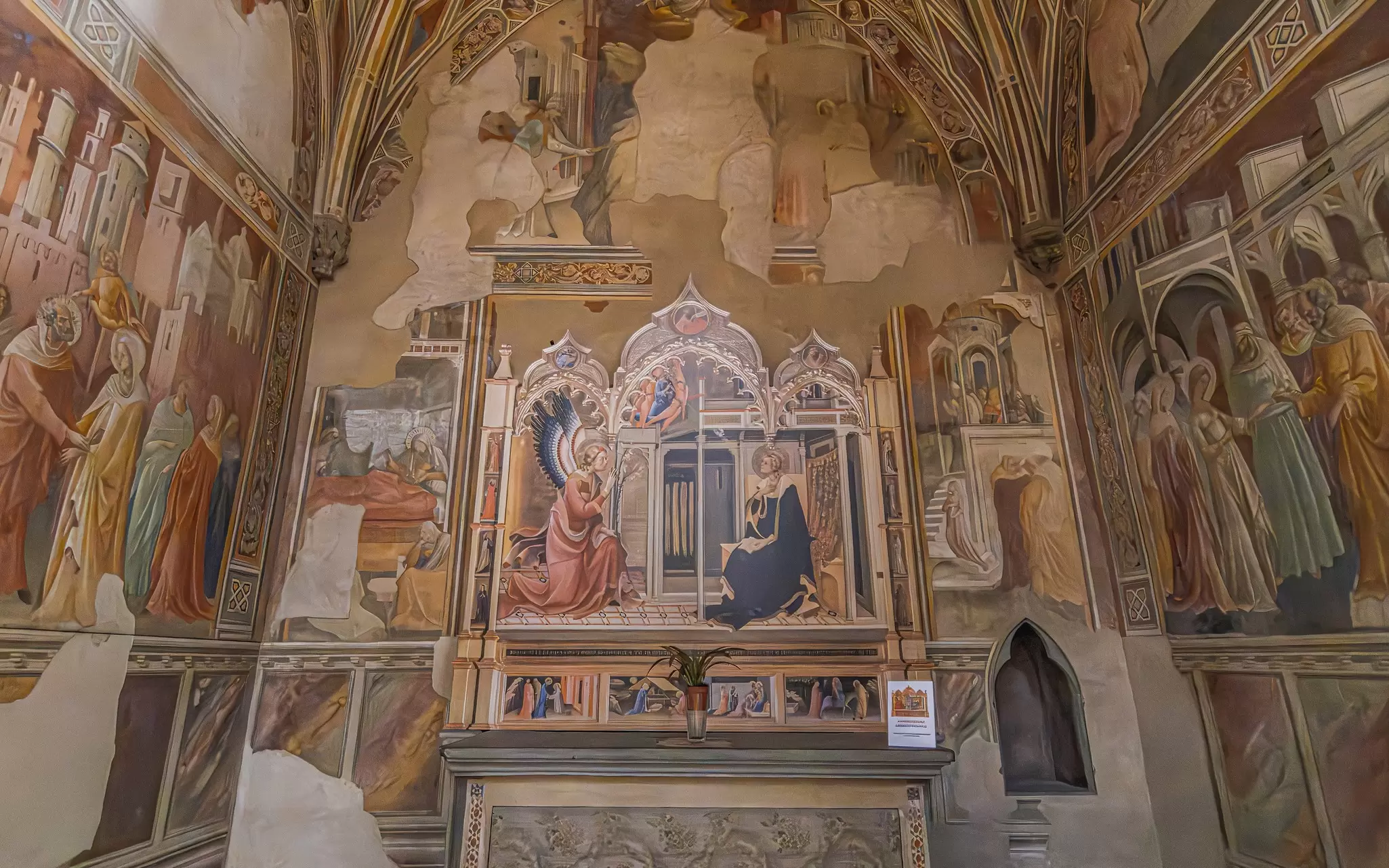 Elaborate frescoes depicting religious figures cover the walls of a chapel in a chruch
