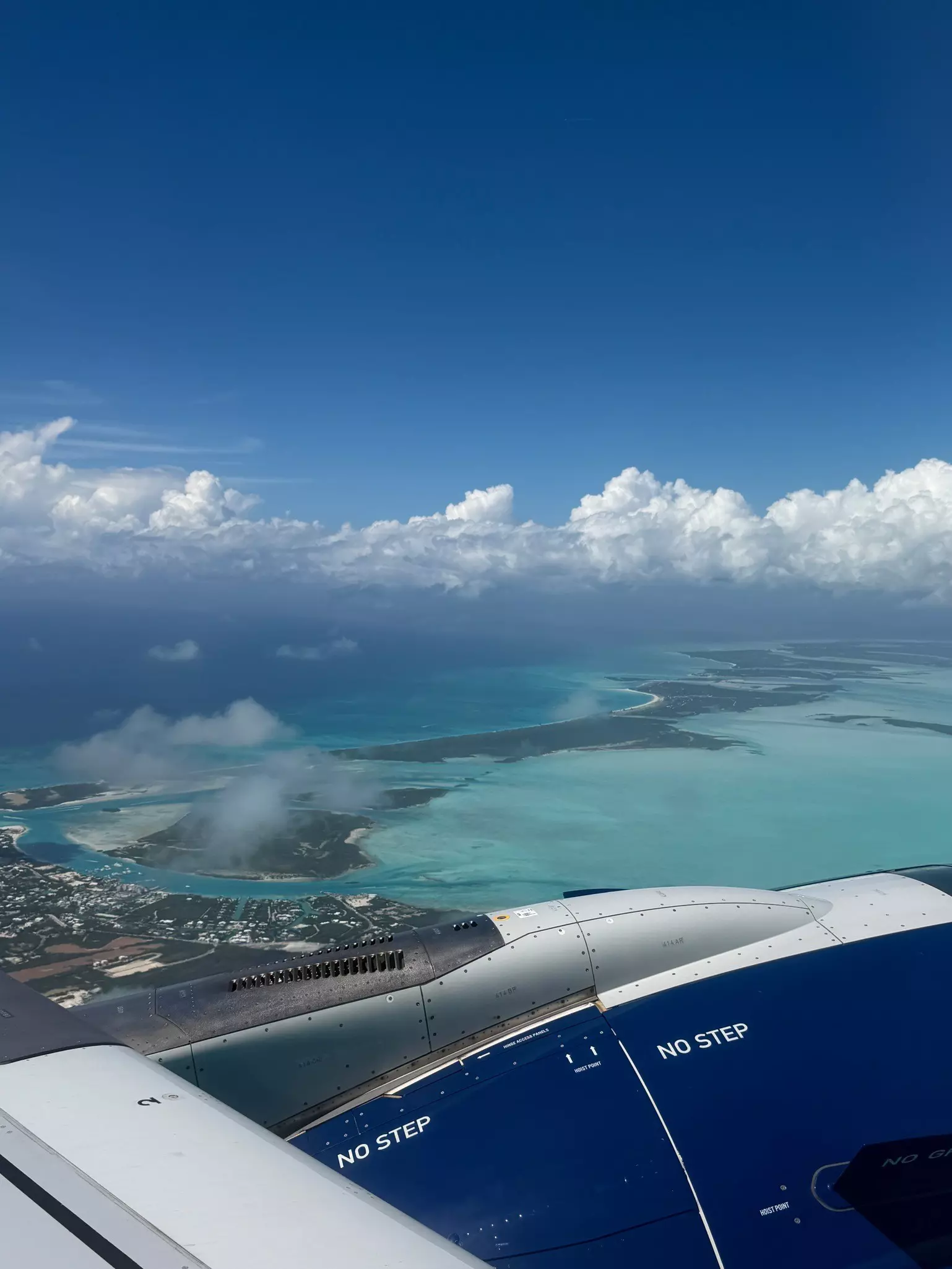 An island with shallow turquoise ocean viewed from an airplane 