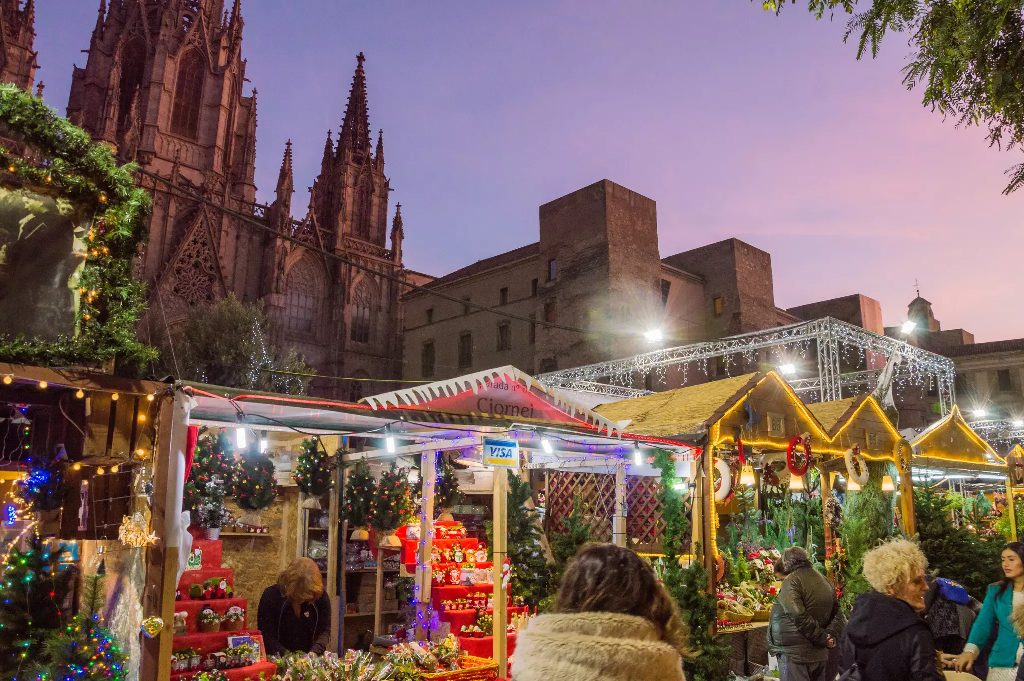 Stalls selling Christmas merchandise are set up in front of a medieval church.