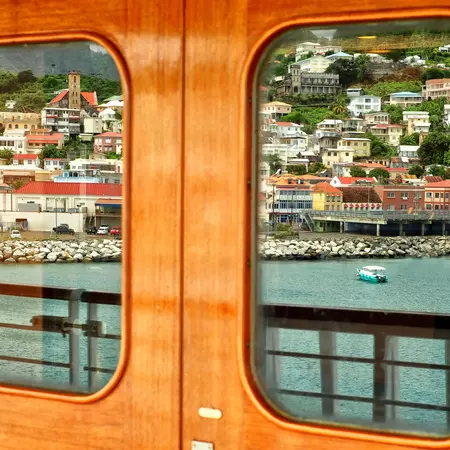 Seaport of island of Grenada reflected in door of ship entering harbor.