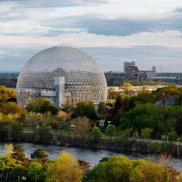 Large spherical structure surrounded by trees and a body of water 