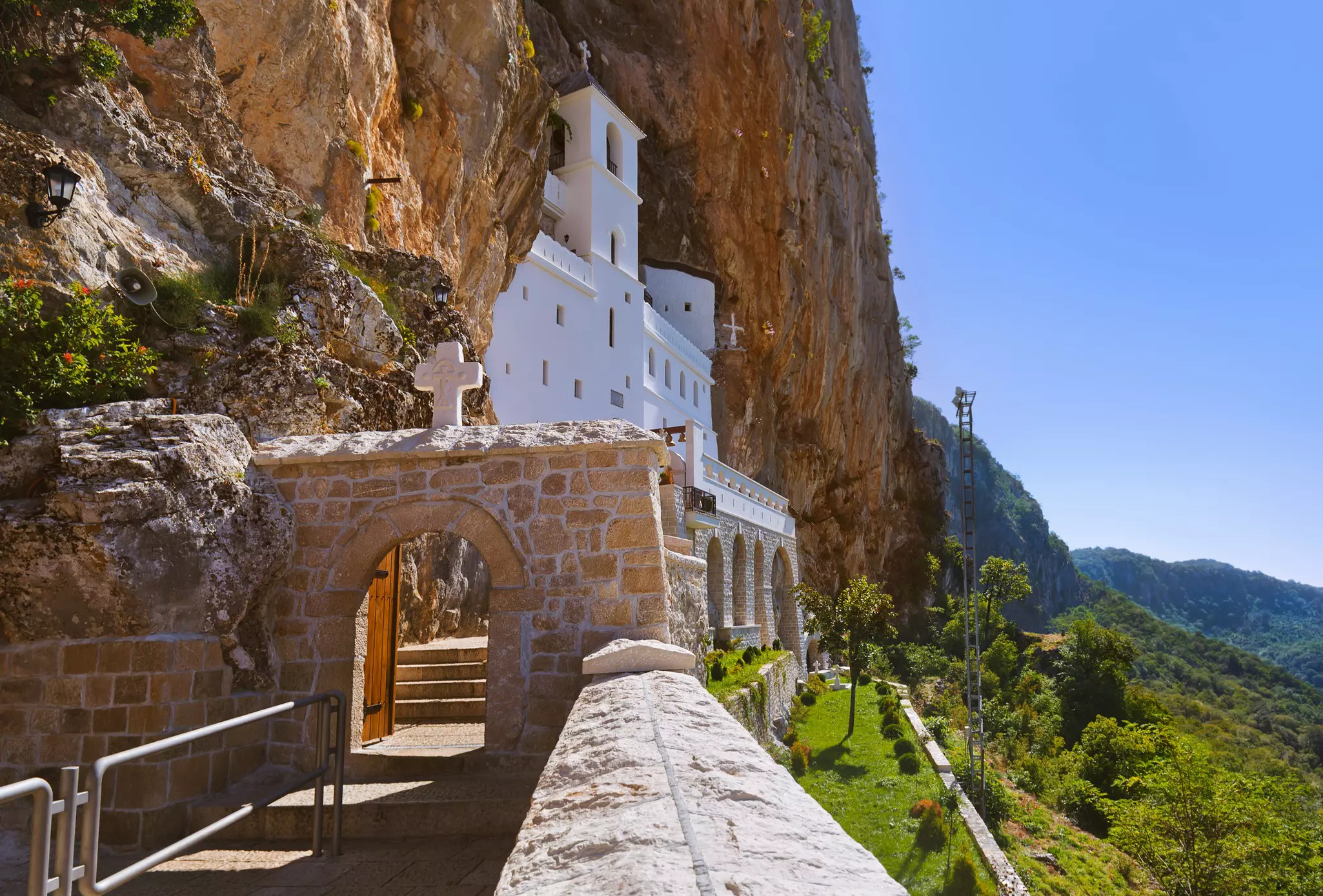 A white monastery building built into the side of a cliff