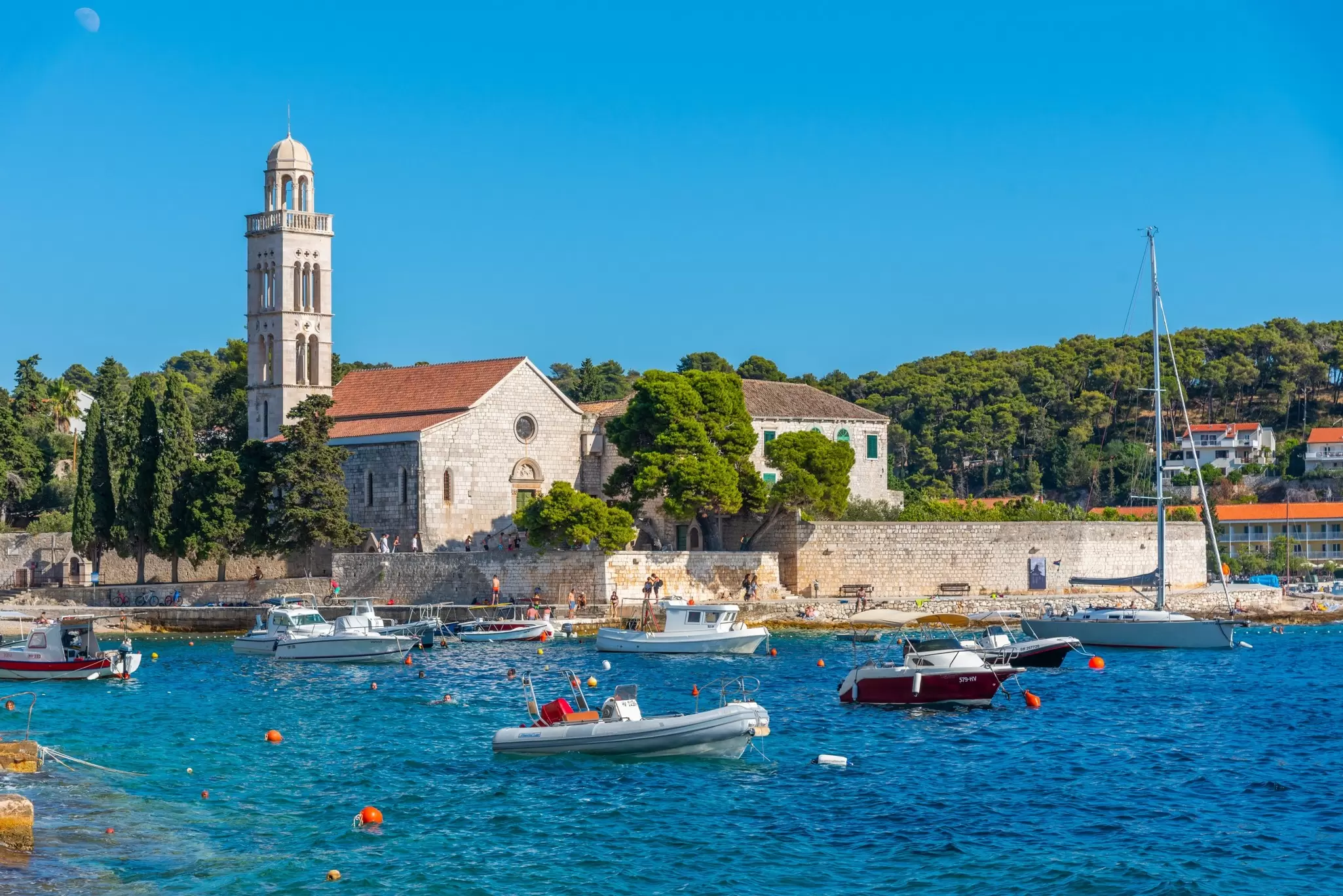 A Franciscan monastery on the shoreline of Hvar, Croatia, with small boats in the bay. 