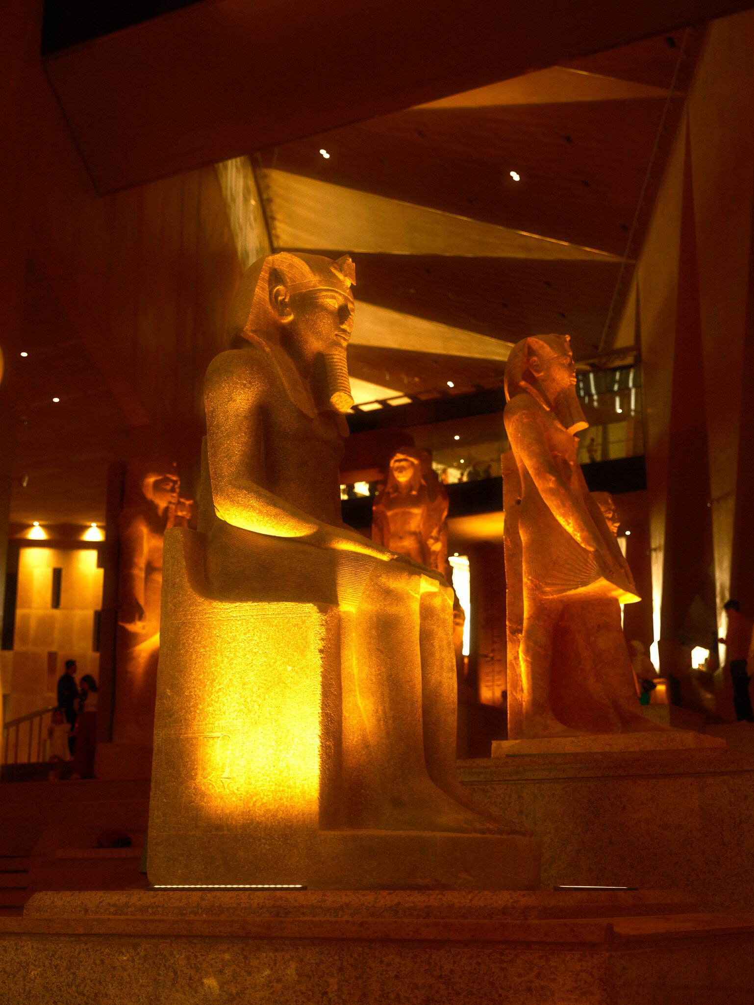 Egyptian statues illuminated in a museum display in Giza