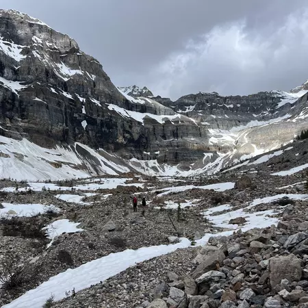 Hikers follow a trail through a snowy valley