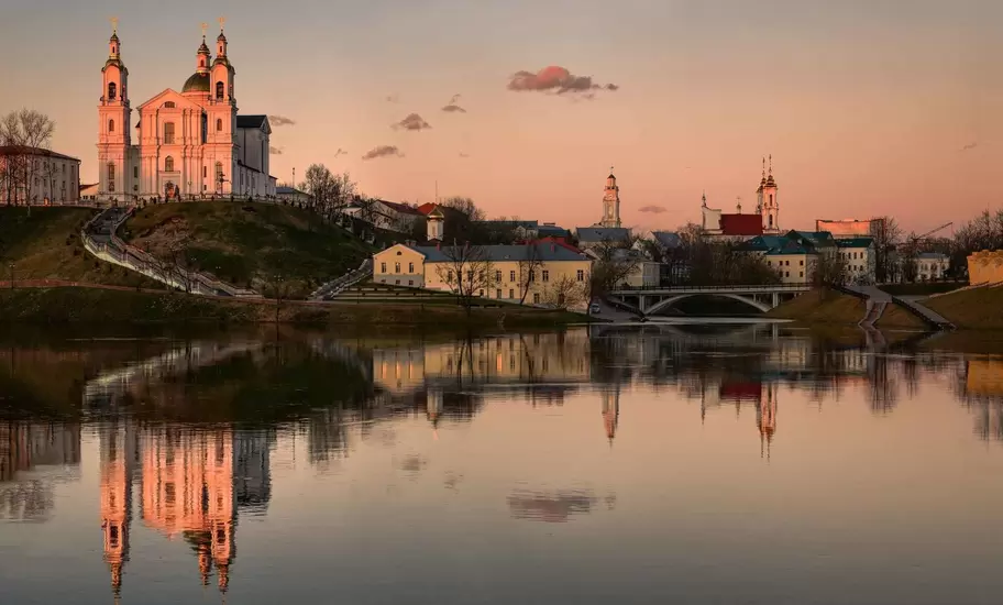 Holy Dormition Cathedral and city hall tower in Vitebsk, Belarus, reflected in the Western Dvina River at sunset