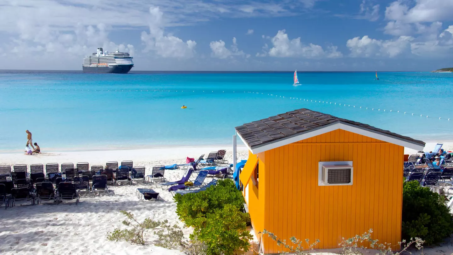 A colourful beach cabana with the Holland America cruise ship Westerdam in background at Half Moon Cay, Bahamas, Caribbean. ©Caribbean/Alamy Stock Photo