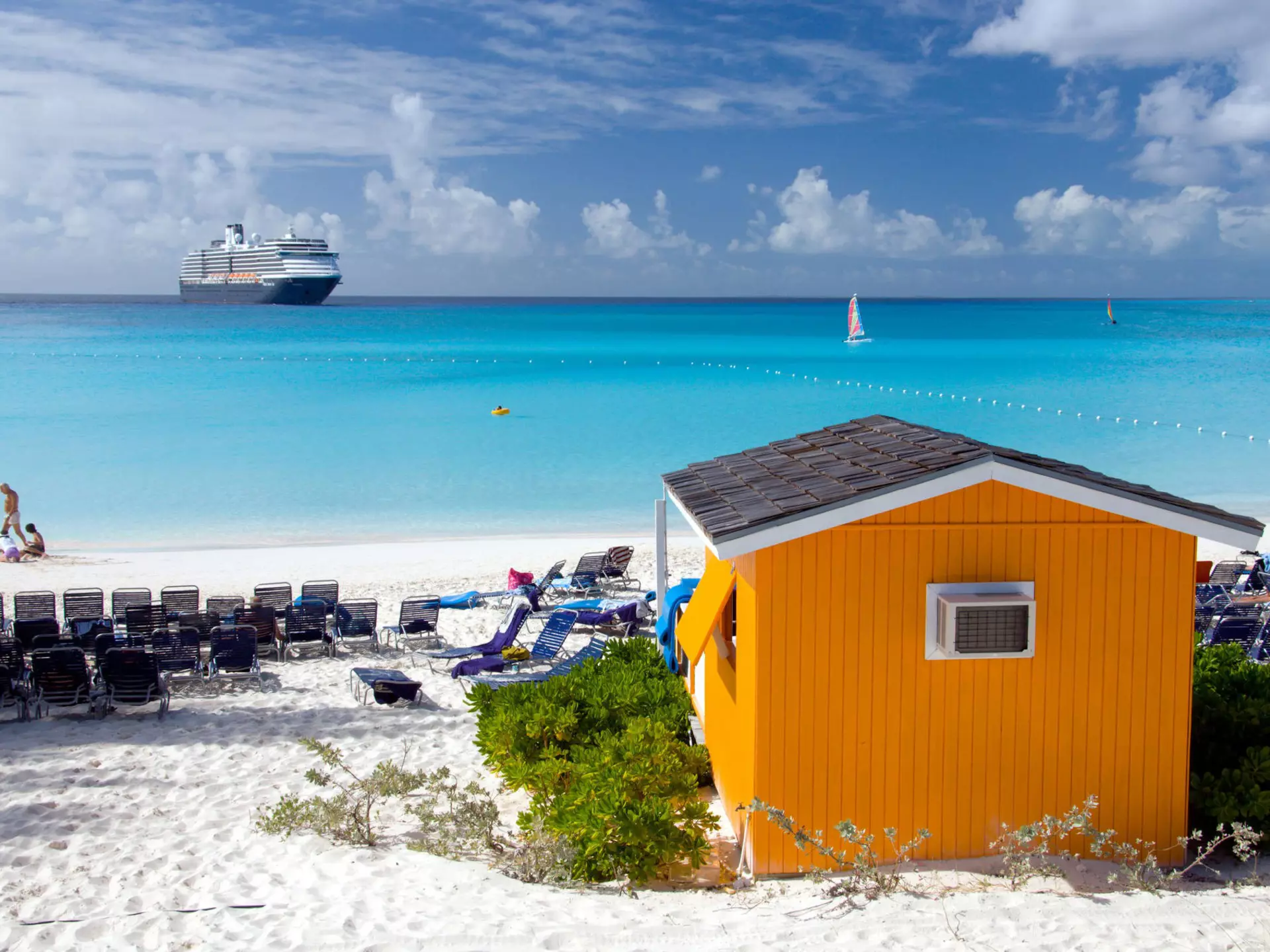 A colorful beach cabana with the Holland American cruise ship at sea in the background
