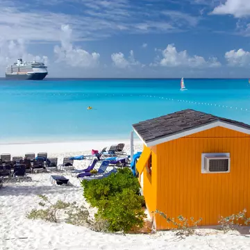 A colorful beach cabana with the Holland American cruise ship at sea in the background