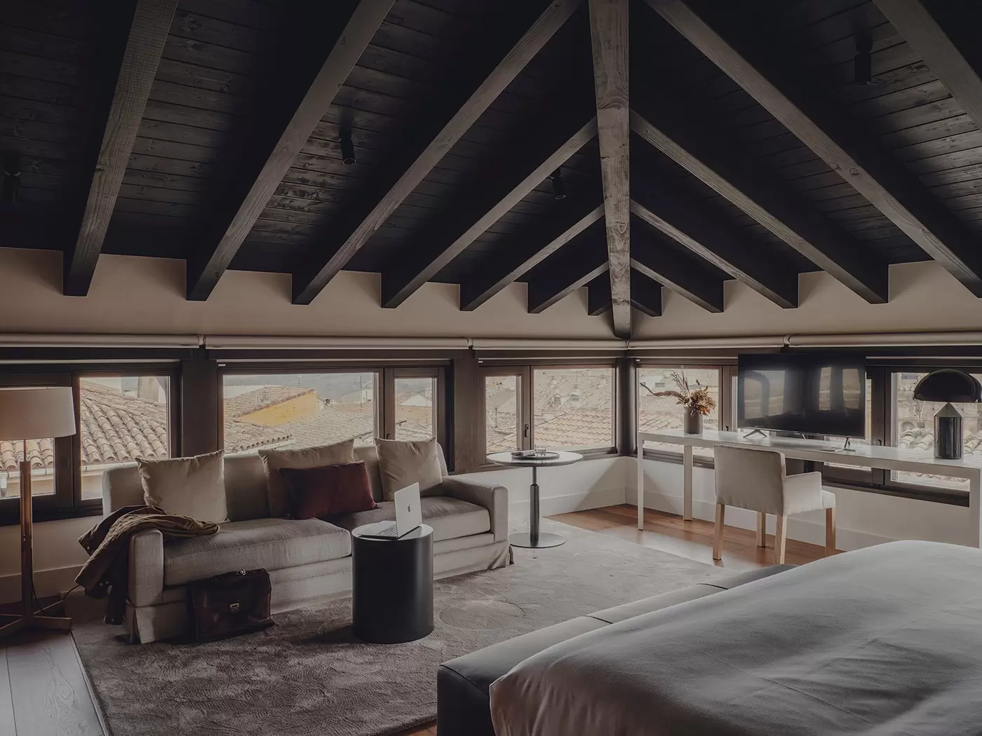 A hotel room with a couch and desk sitting under windows. Santa María Briones hotel in La Rioja, Spain