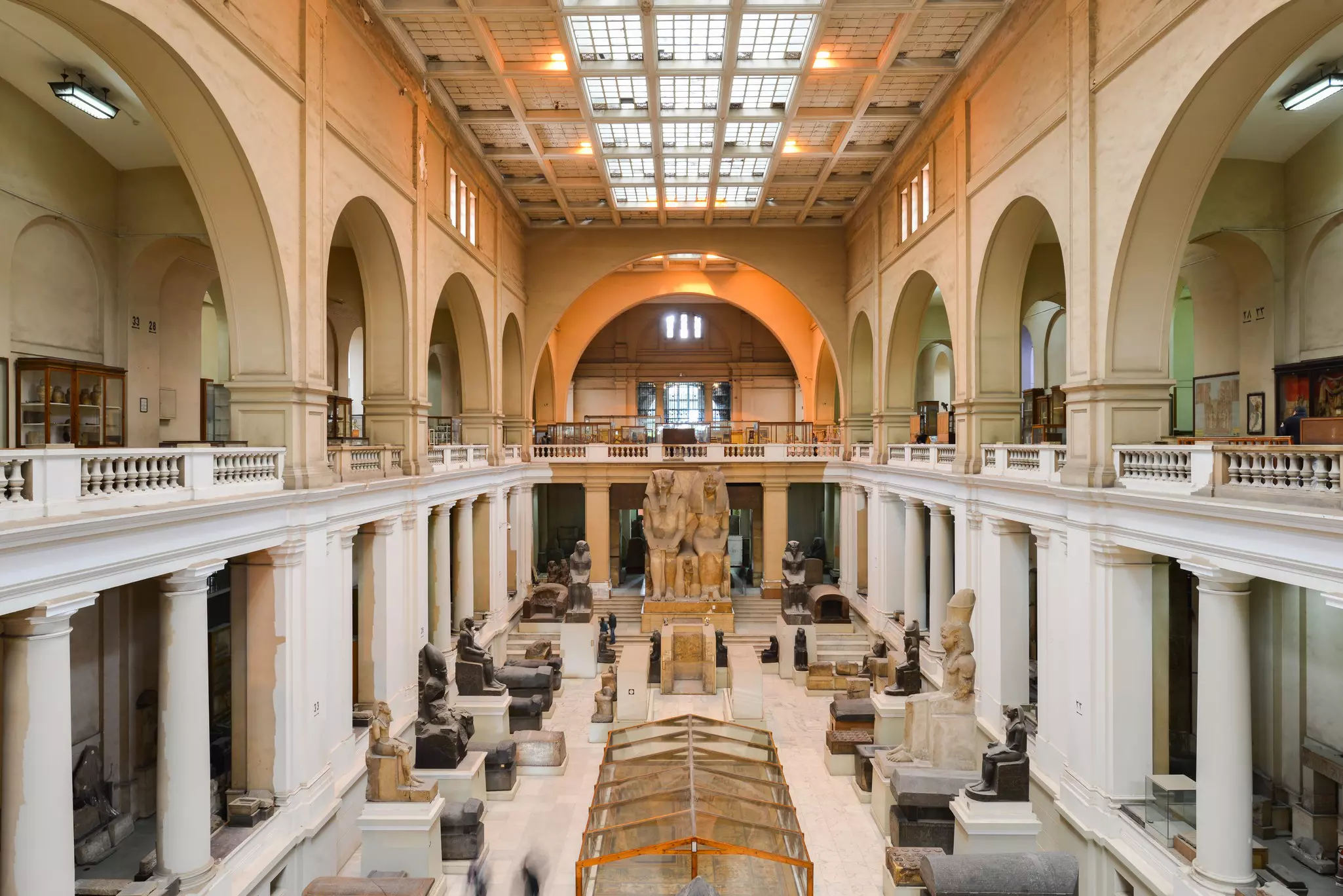 Interior of a vast museum hall displaying Egyptian sculptures and statues.