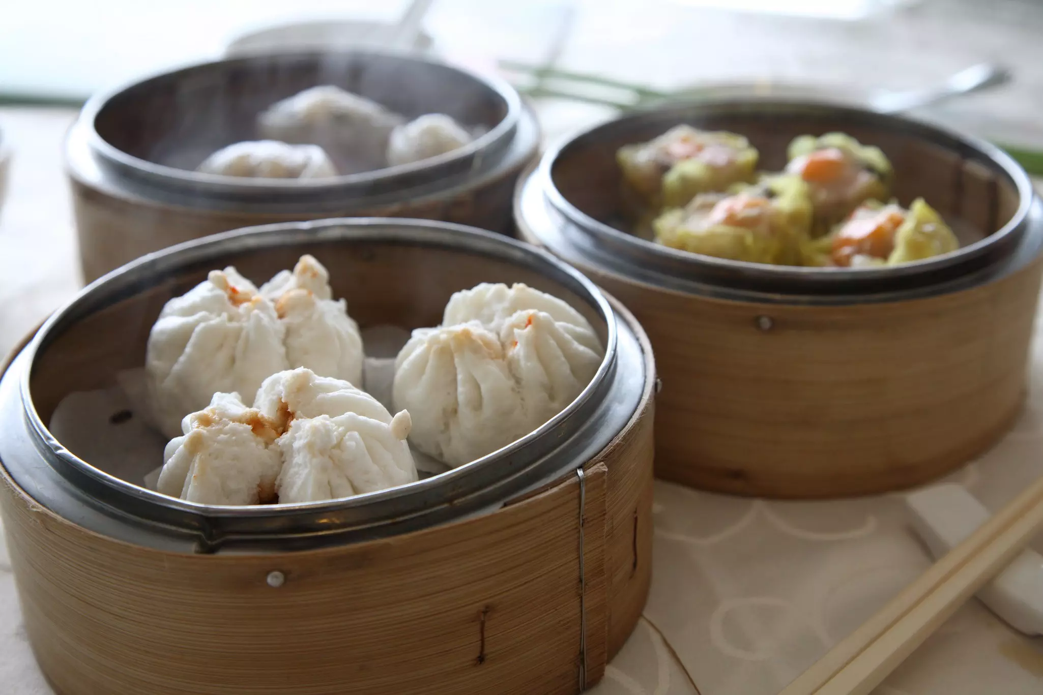 White steamed buns in three brown bamboo dishes