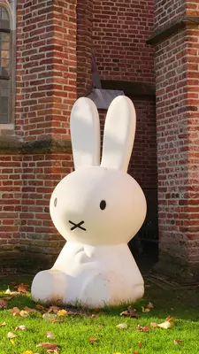 A giant stuffed bunny leans against a church wall.