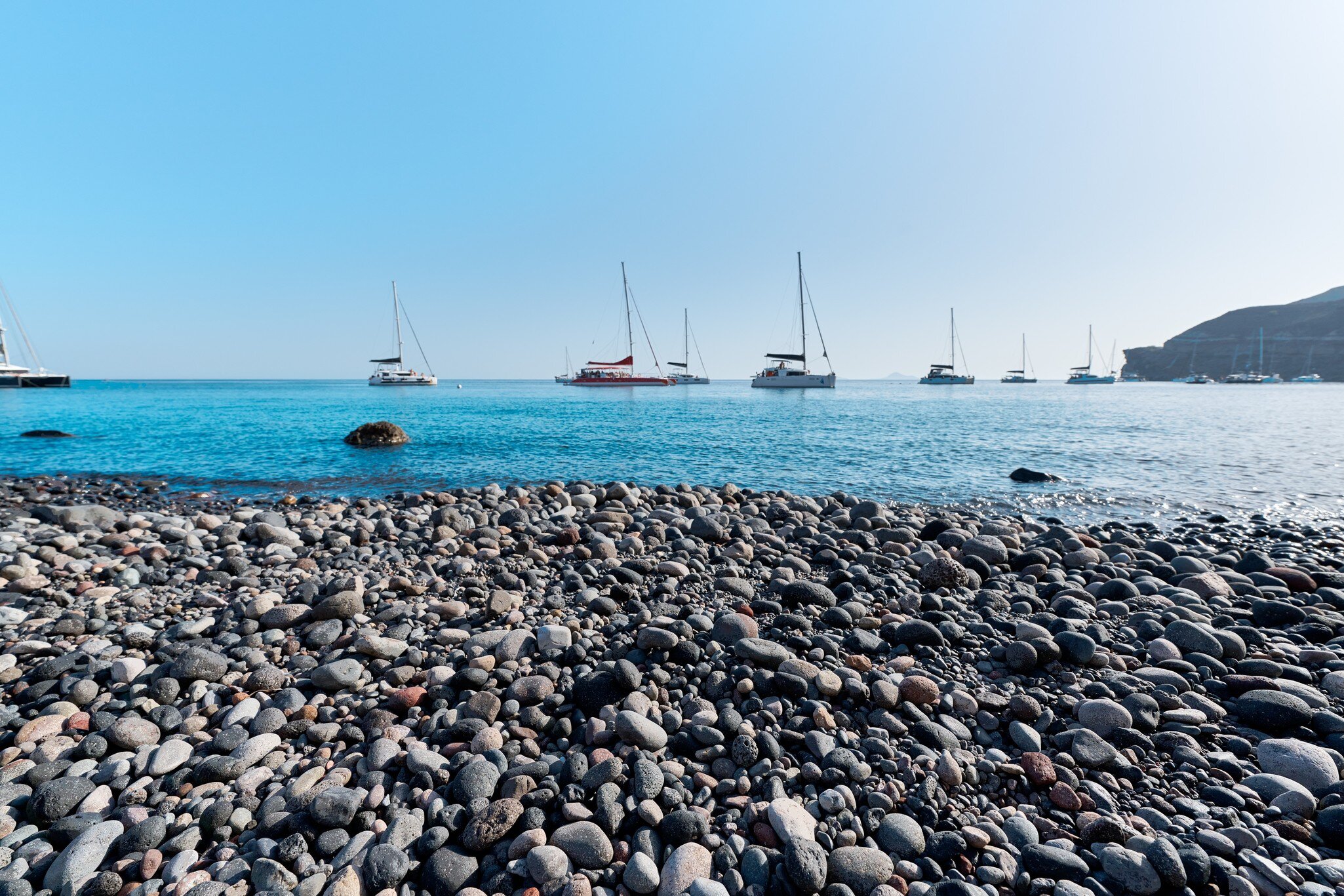 View of boats out on the water from Mesa Pigadia Beach on the island of Santorini in Greece.