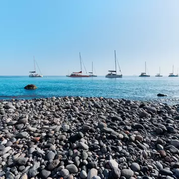 View of boats out on the water from Mesa Pigadia Beach on the island of Santorini in Greece.