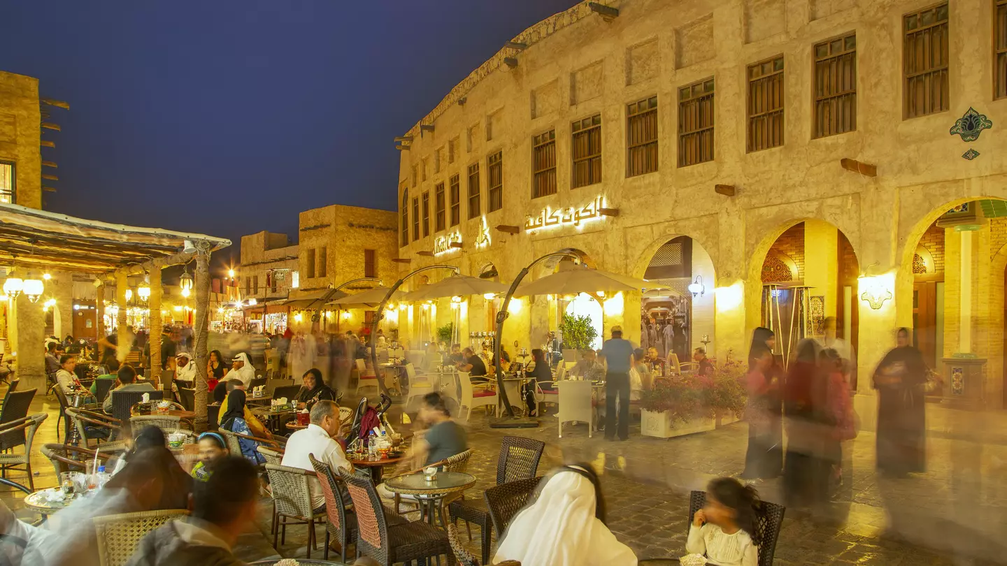Illuminated traditional houses and people in outdoor restaurants in the historical district of Doha.