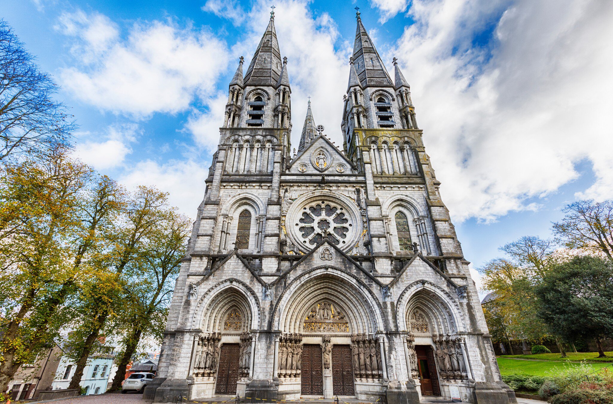 Central facade of St. Fin Barre's Cathedral in Cork, Ireland. Low angle with blue cloudy sky in the back.