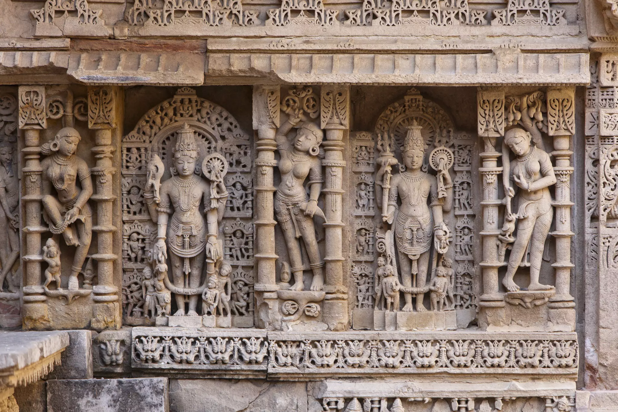 Ornate stone carvings of gods and goddesses surrounded by pillars and intricate detail.
