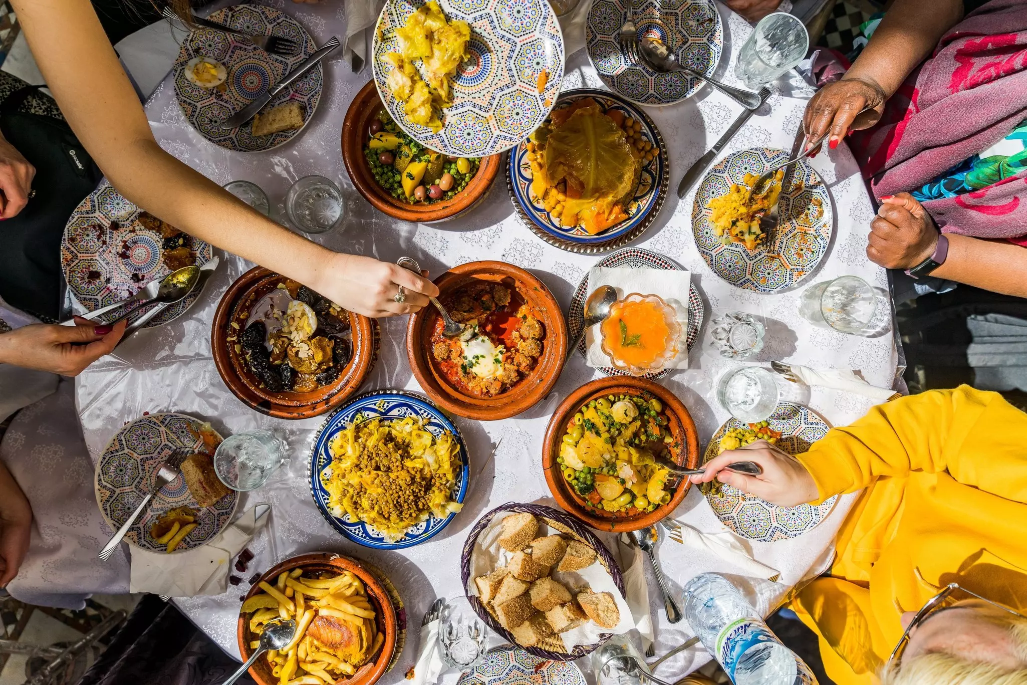 Top view of a colorful Moroccan meal with traditional tagines and dishes shared among friends, showcasing vibrant cuisine and cultural dining in Morocco.