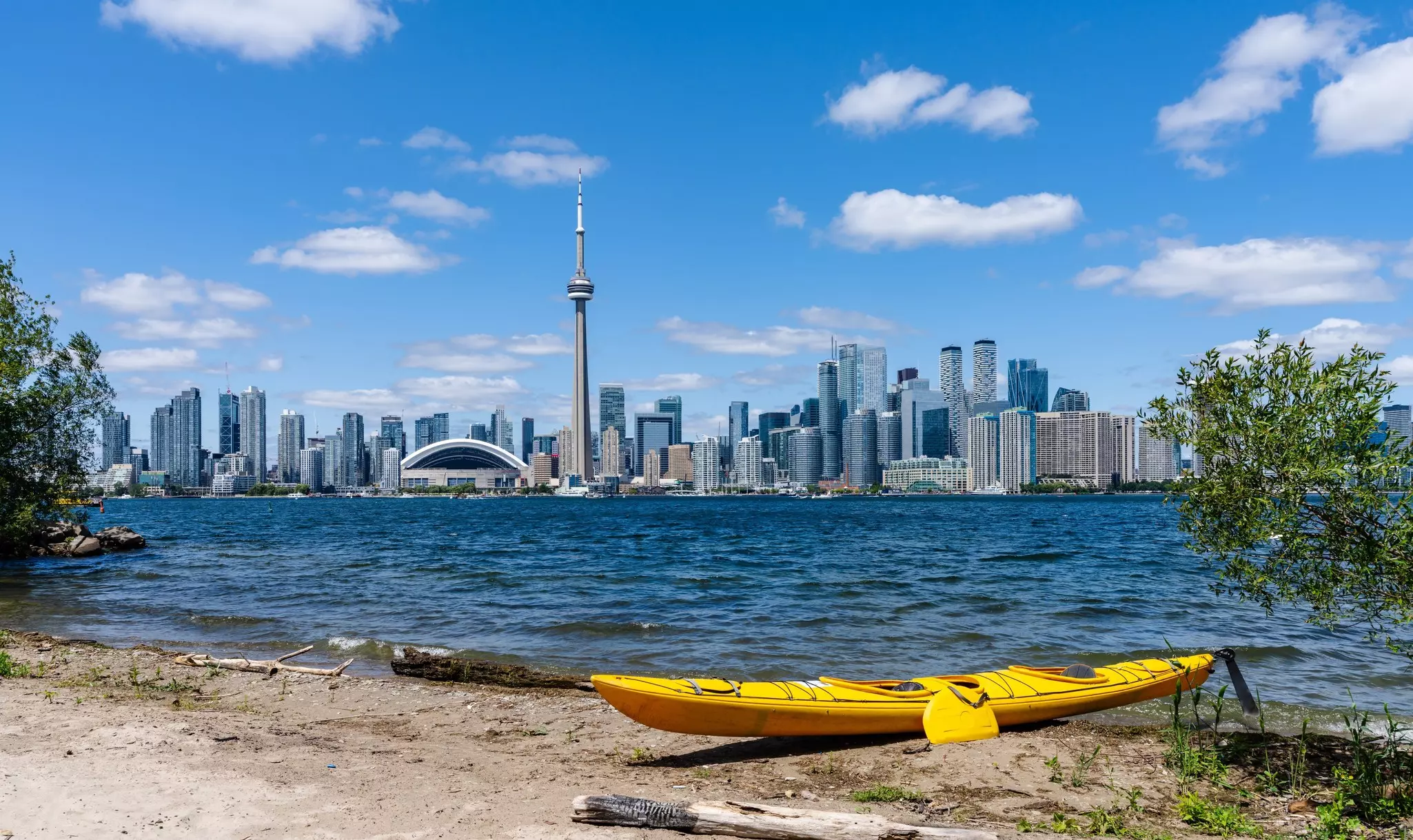 The Toronto skyline with a kayak parked on the shores of the city islands in the foreground.