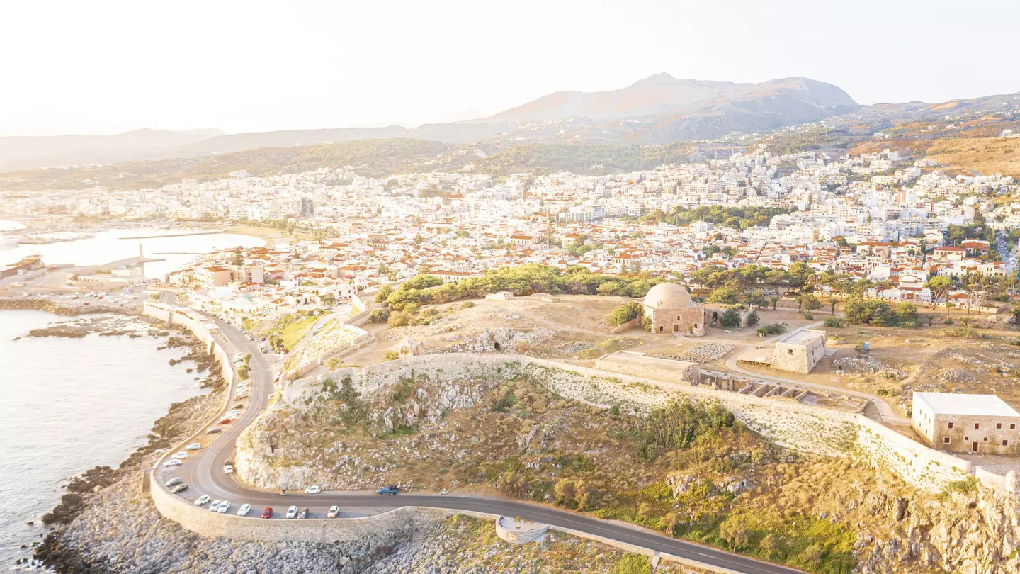 Aerial view of an old fortress on the hill with a road running along the coast