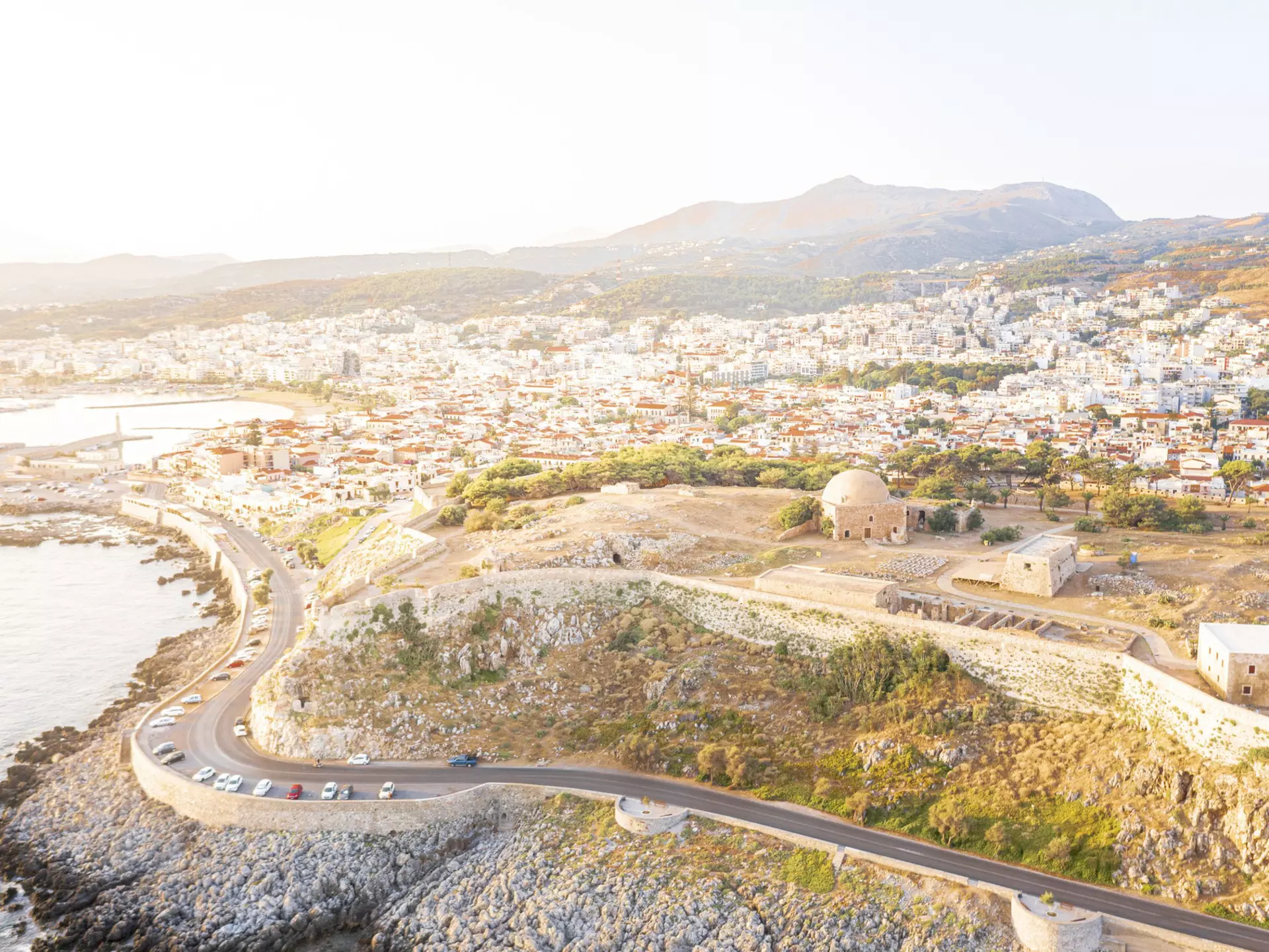 Aerial view of an old fortress on the hill with a road running along the coast