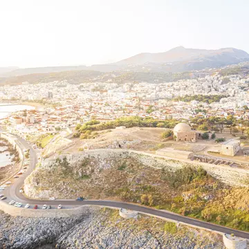 Aerial view of an old fortress on the hill with a road running along the coast