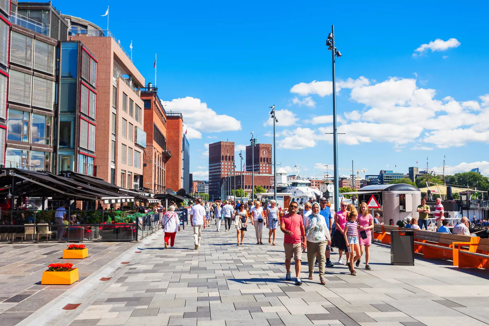 A waterfront pedstrianized area lined wtih bars and restaurants on a sunny day.